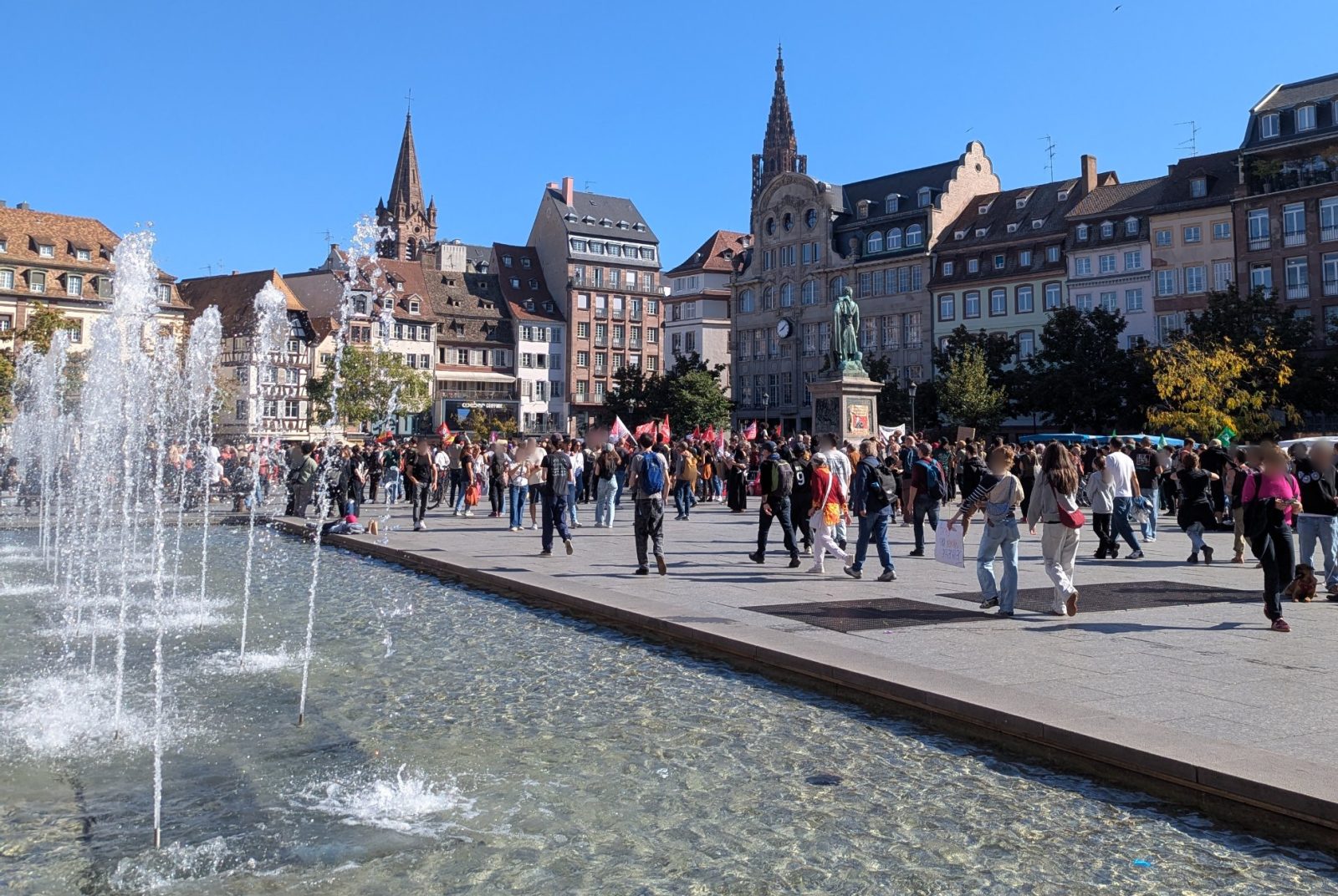 La place Kléber à Strasbourg, le 6 octobre 2026 vers 14 h, au départ du cortège, avec la fontaine au premier plan et la statue de Kléber au fond.