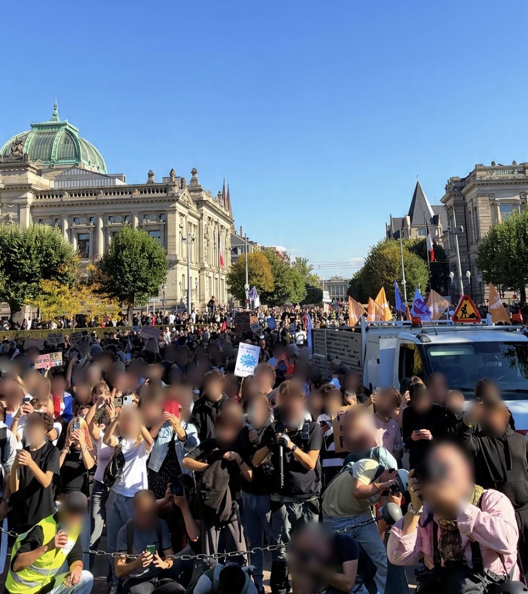 Place de la République : une foule de jeunes, téléphones levés, des photographes de presse au premier rang derrière une chaîne, des drapeaux et une camionnette ; au fond, des bâtiments sous un ciel bleu.