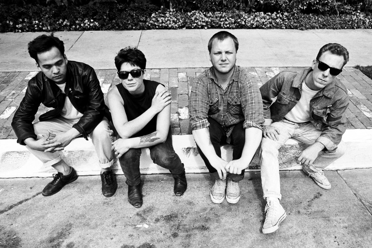 Les Pixies assis sur un trottoir : Joey Santiago, Kim Deal, David Lovering et Charles Thompson